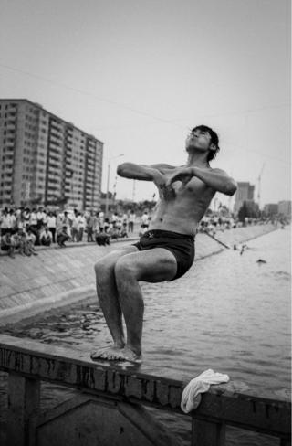 A man jumps backward into the sea