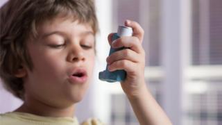 Boy using a blue inhaler for asthma
