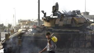 An Iraqi fireman walks past a damaged US. Army armoured vehicle in the Shiia-majority Sadr city neighbourhood of Baghdad (13 August 20005)