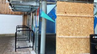 A wooden panel covers a broken window at the Warrington Peace centre