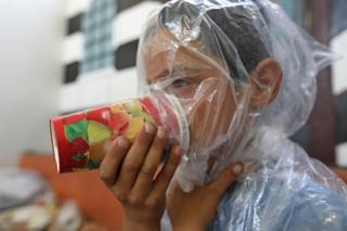 A Syrian child tries an improvised gas mask