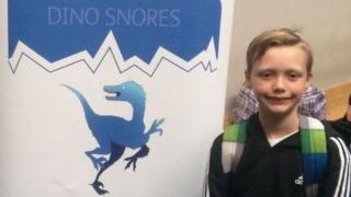 Charlie y su hermano Ronnie frente a un afiche que anuncia la exposición de los dinosaurios en el Museo Nacional de Historia de Londres.