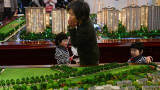 Mulher com os filhos em feira imobiliária na China