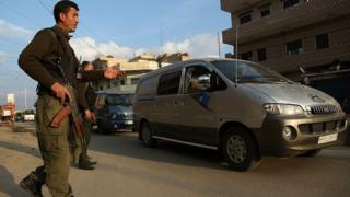 Members of the Kurdish security forces ,known as the Asayish, check vehicles on 16 December 2015 in the north-eastern Syrian city of Qamishli