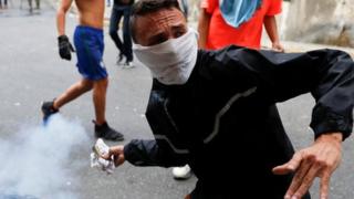 A protester throws back a tear gas canister during clashes with security forces in Caracas on 23 January