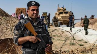 A member of Kurdish security forces stands guard during a demonstration by Syrian Kurds against Turkish threats