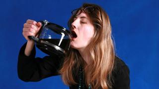 Mujer exhausta tomando café directo de la cafetera