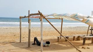 A man lying down on a deserted beach in Accra, Ghana - Monday 31 March 2020