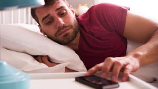 Homem mexe em despertador no celular