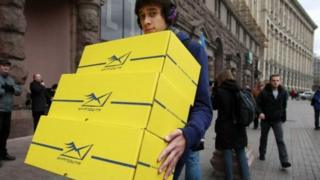 Чоловік несе посилки Укрпошти