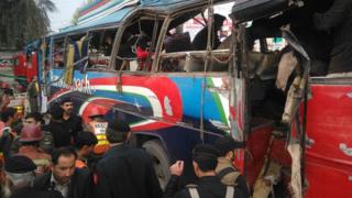 Pakistani police officials search a damaged bus after bomb blast in Peshawar