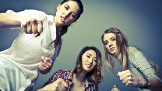 Tres mujeres en actitud de pelea contra un enemigo común.