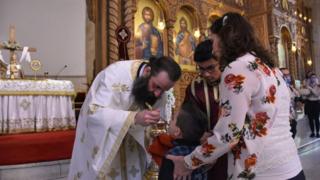 Ein Kind nimmt nach der Sonntagsmesse in der Kirche Saint Elias in Aleppo, Syrien, am 10. Mai 2020 die Kommunion eines römisch-orthodoxen Priesters entgegen