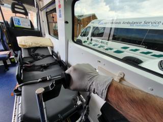 A carer holds a stretcher in an ambulance