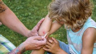 Padre atendiendo una niña con un corte menor en el brazo