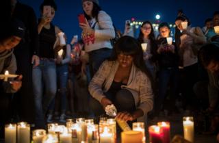 A woman lights a candle in Las Vegas as a tribute to those killed in a gun attack in the city