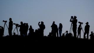 Silhouetted media members and people documenting the full moon, also known as the Supermoon or Flower Moon, over Primrose Hill, are seen in London, Britain