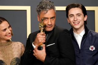 Taika Waititi holds his Oscar