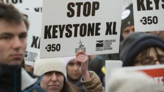 A woman holds up a placard saying "Stop Keystone XL"