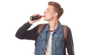 Joven tomando una botella de cola.
