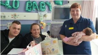 The new mother of Ellie, with father Dan Taylor and nurse Bobby Bedford carrying the girl 