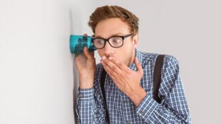 Una persona espiando una conversación con un vaso pegado a una pared