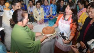 လေလံအောင်သူကို ဒေါ်အောင်ဆန်းစုကြည်ဓာတ်ပုံနဲ့ လက်မှတ်ထိုးထားတဲ့ အေပရွှန်တစ်ခုကိုလည်းပေးအပ်ခဲ့