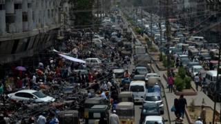 Commuters make their way along a busy street in a market area after the government eased the nationwide lockdown in Karachi on 14 May