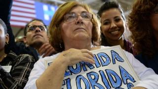Una señora sostiene una pancarta que dice "Florida"
