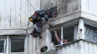 A specialist inspects the damaged facade of a multi-storey apartment building after a reported drone attack in Moscow on May 30, 2023