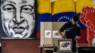 Joven votando delante de un mural de Chávez