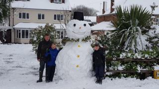 Family with snowman in garden
