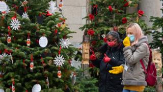 Woman in face masks looking at Christmas trees