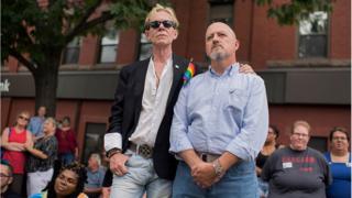 Pareja homosexual con una pequeña bandera del movimiento gay