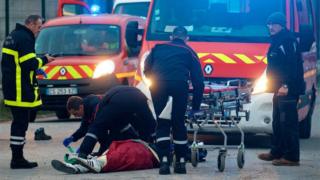 Мигрант получает медицинскую помощь от спасателей после столкновений возле паромного порта в Кале, на севере Франции, 1 февраля 2018 года.