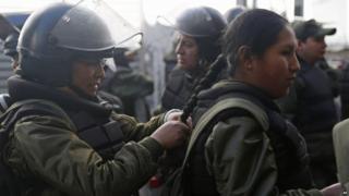 Female police in full riot gear braid each other's hair before in La Paz, Bolivia, on 22 July 2015
