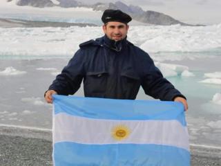 Marinheiro com bandeira da Argentina em frente a uma geleira