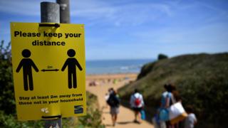 Social distancing reminder sign at a UK beach