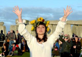 A reveller enjoys the sunrise at Stonehenge in Wiltshire