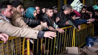 Migrants wait for free blankets and raincoats before disembarking from a ferry in the port of Piraeus near Athens on December 10, 2015