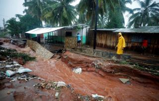 A man walks past flood damaged houses in the aftermath of Cyclone Kenneth in Pemba, Mozambique