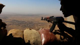 Guerrilheiros curdos montam guarda em uma colina a 25km de Mosul