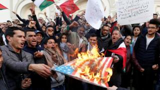 Protesters burn a US flag