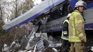 Rescuers stand in front of a carriage at the site of the two crashed trains