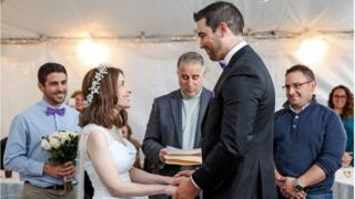 Nicole and Danny Rios hold hands and smile as they get married