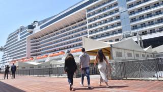 People on their way to board the MSC Grandiosa cruise ship at a port in Genoa, northern Italy