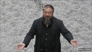 Ai Weiwei poses with his installation Sunflower Seeds at the Tate Modern gallery in London in October 2010