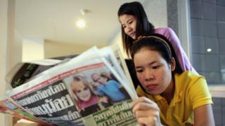 Resepsionis membaca koran dengan sampul kasus JonBenet Ramsey