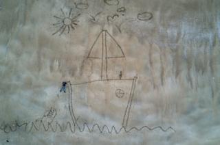 An image created in the sand representing Ugo in difficulty in the open sea