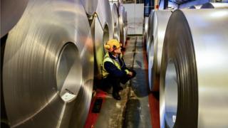 A worker inspects rolls of steel